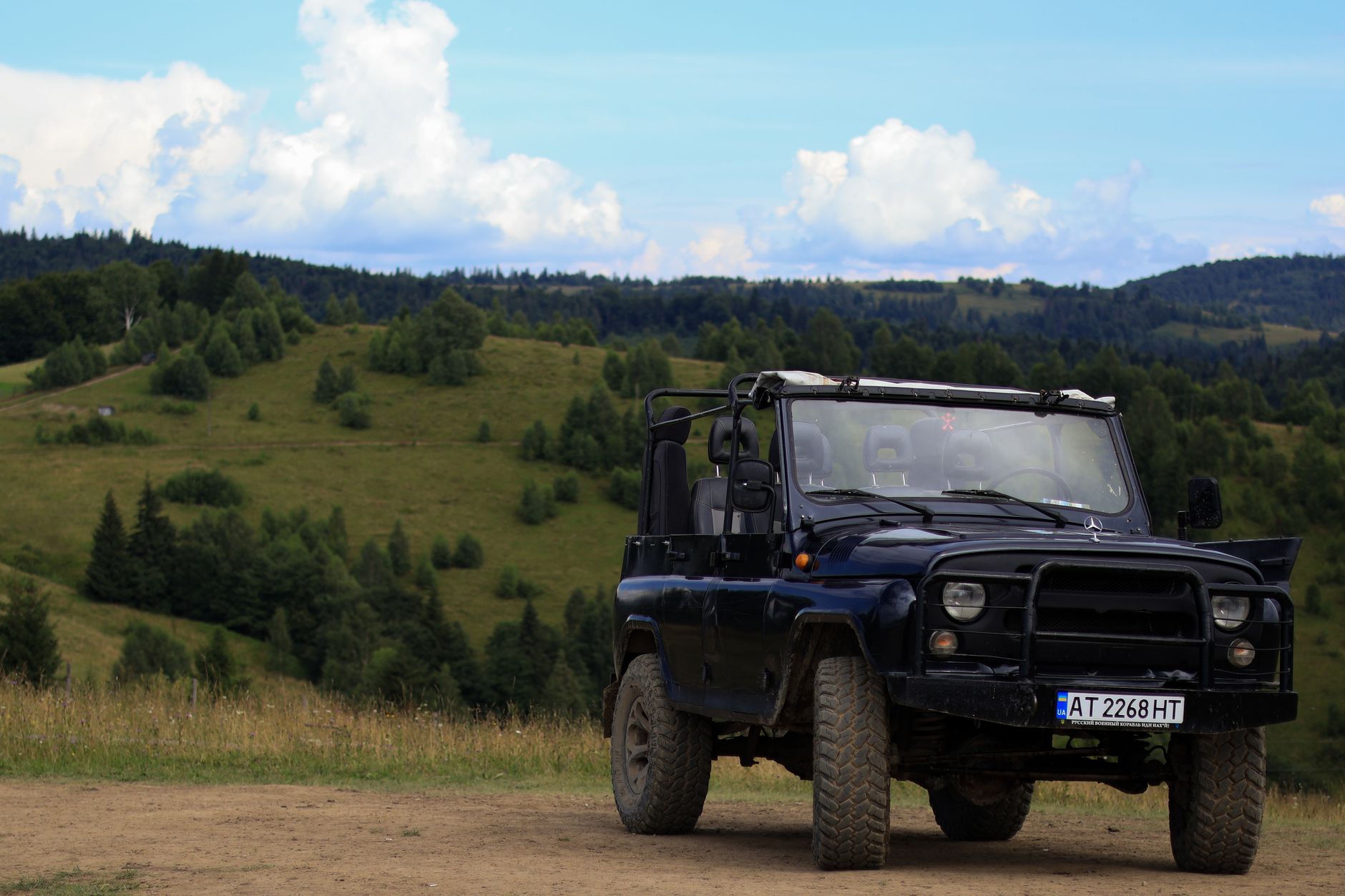 A white 4x4 off-road vehicle driving along a narrow, rocky road in the Caucasus Mountains