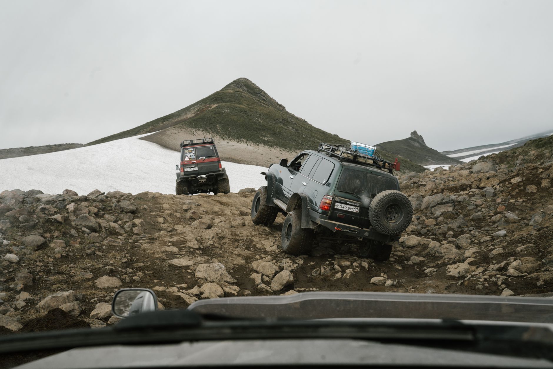 A jeep driving along a narrow road in the Adjara mountains against a backdrop of green forests