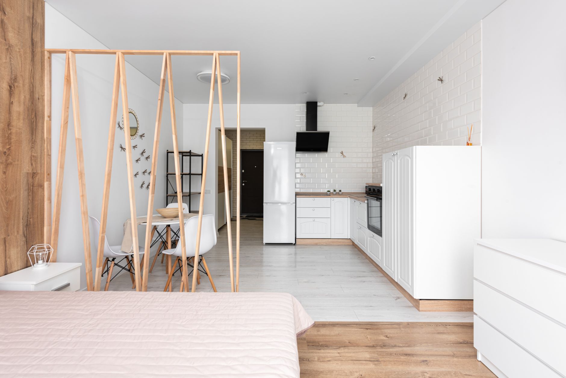 Modern small apartment interior in light colors, with a bedroom separated by a glass partition and functional furniture.