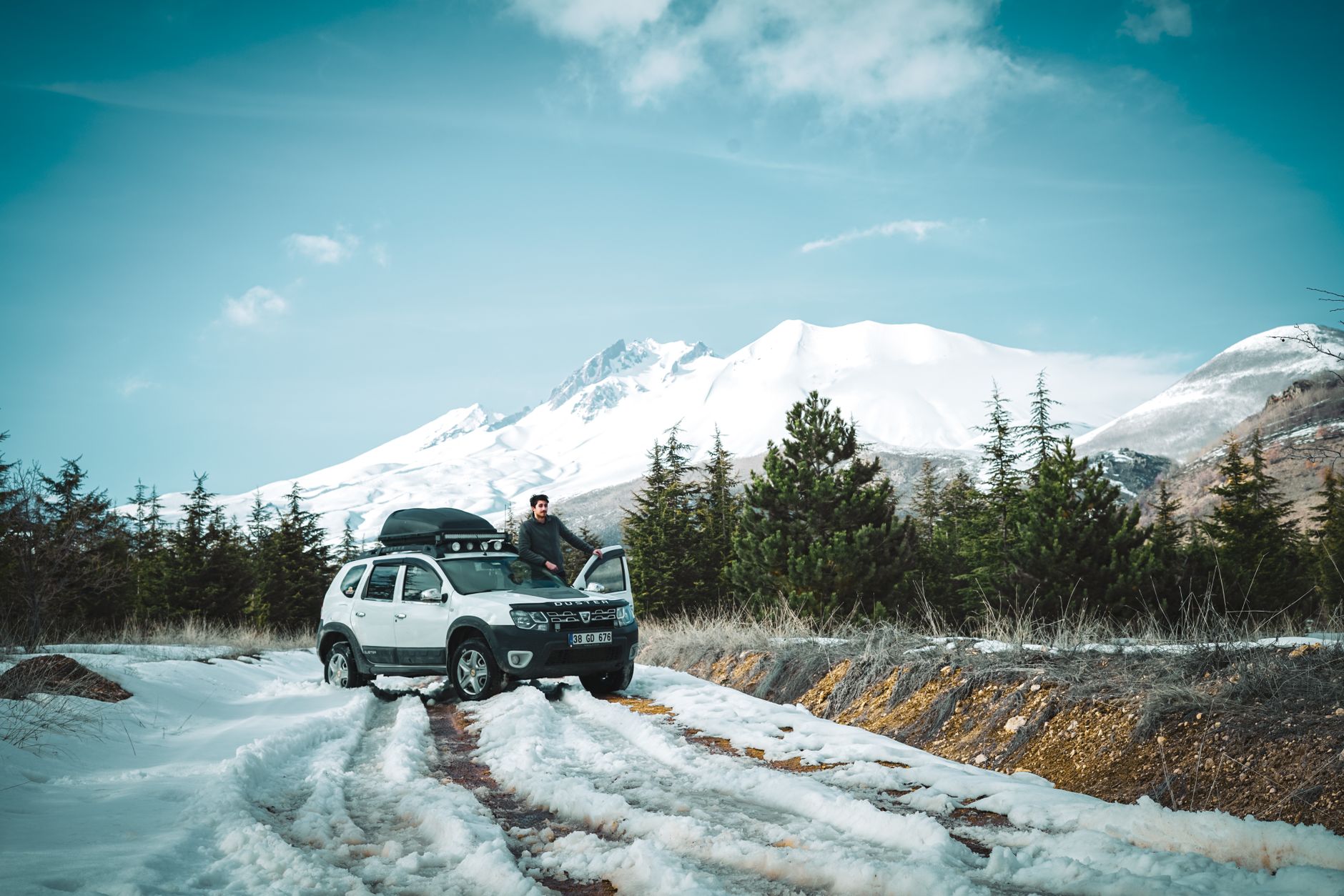 White SUV on a mountain road with a view of Kazbegi, in the context of travel planning.