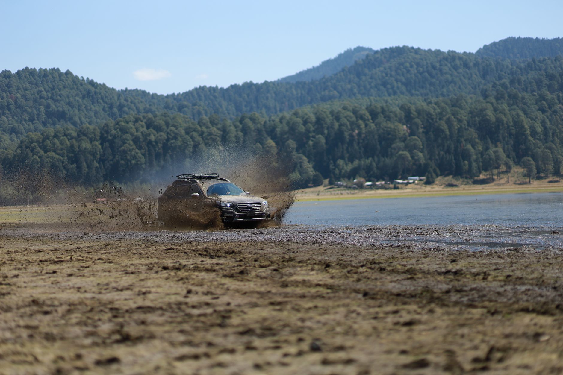 A white SUV driving along a beautiful, unpaved mountain road through the Caucasus Mountains