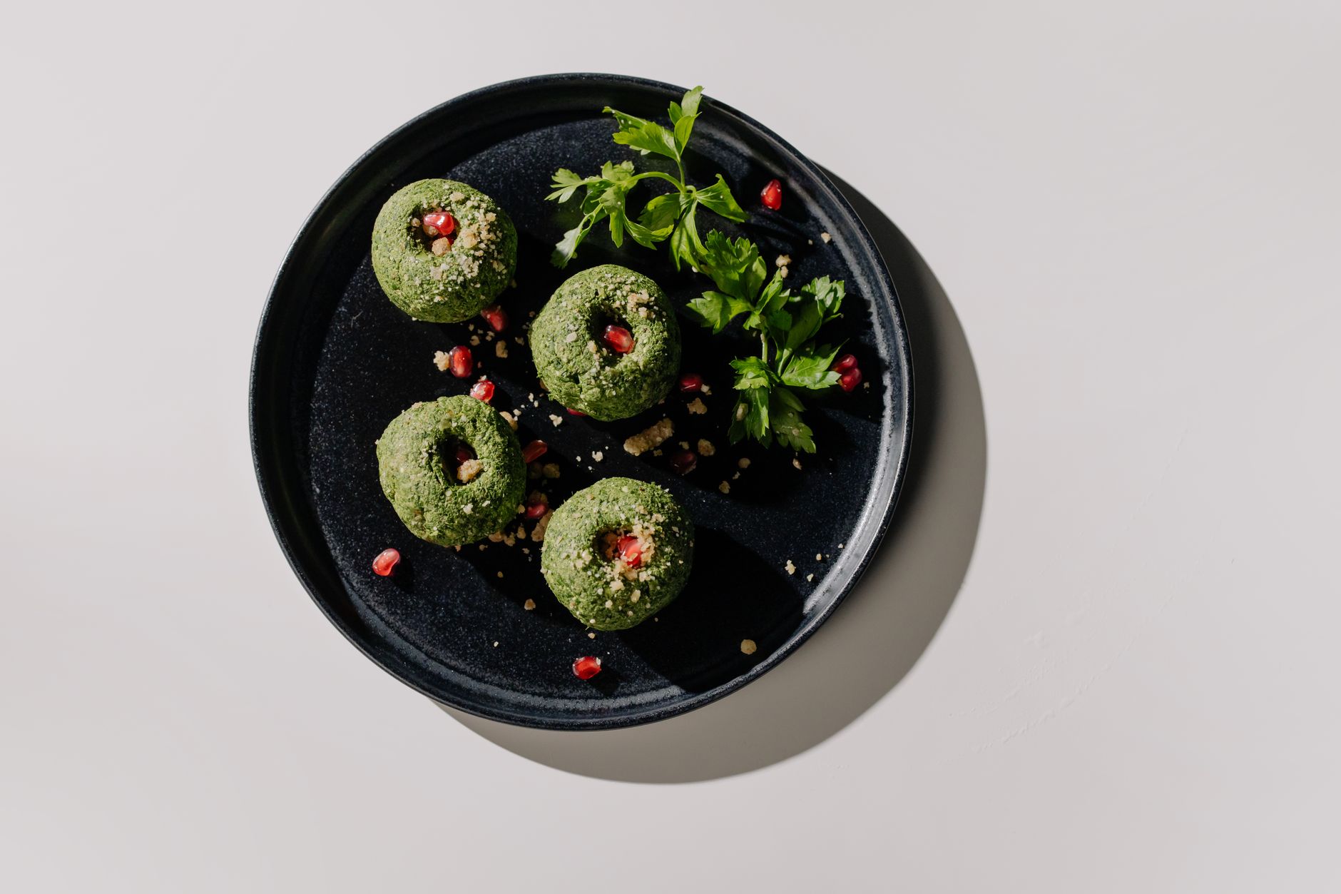 Green pkhali with walnuts and pomegranate seeds on a clay ketsi