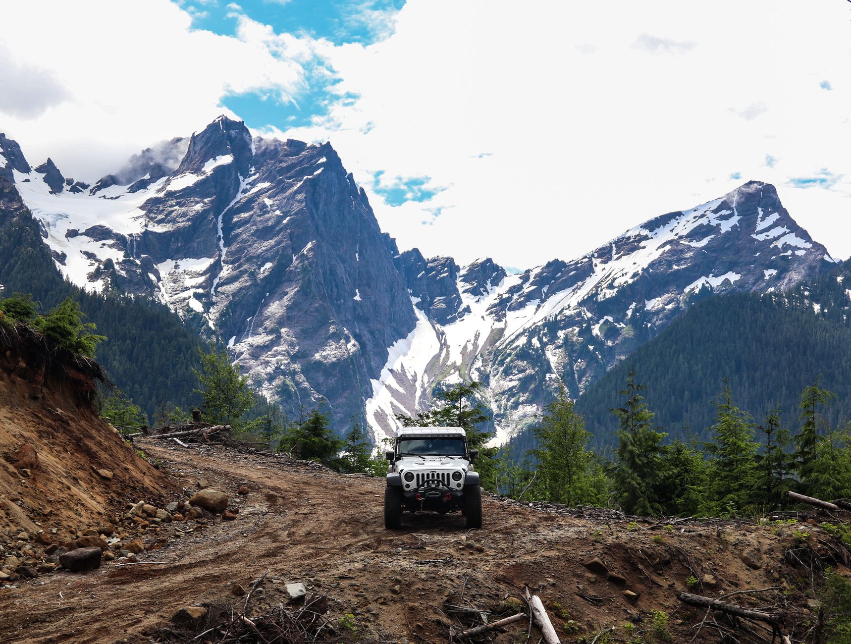 A white 4x4 jeep driving along a narrow rocky path in the Egrisi Range at sunset.