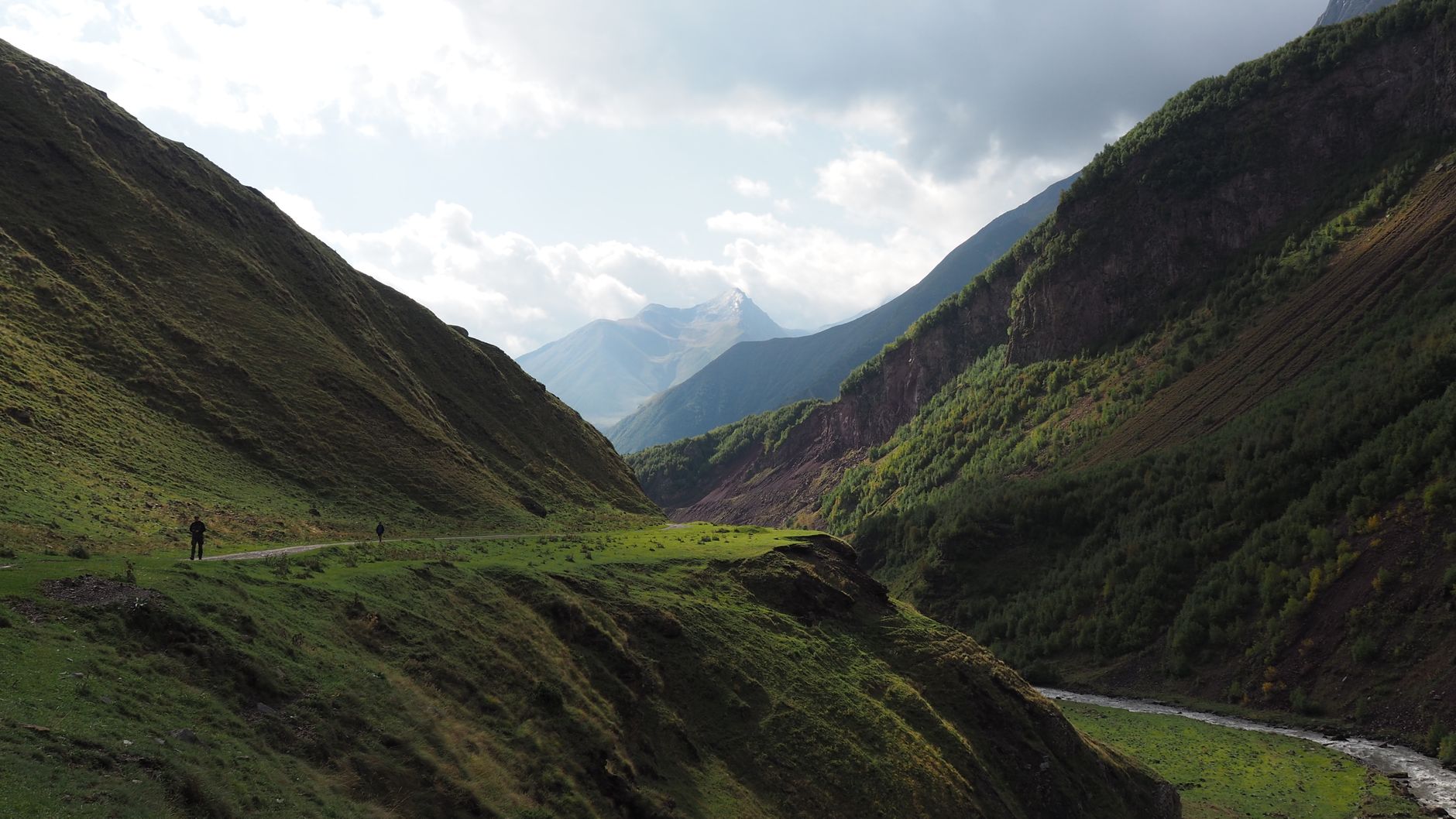 A view of Truso Valley with a river, mineral springs, and the Caucasus Mountains in the background.