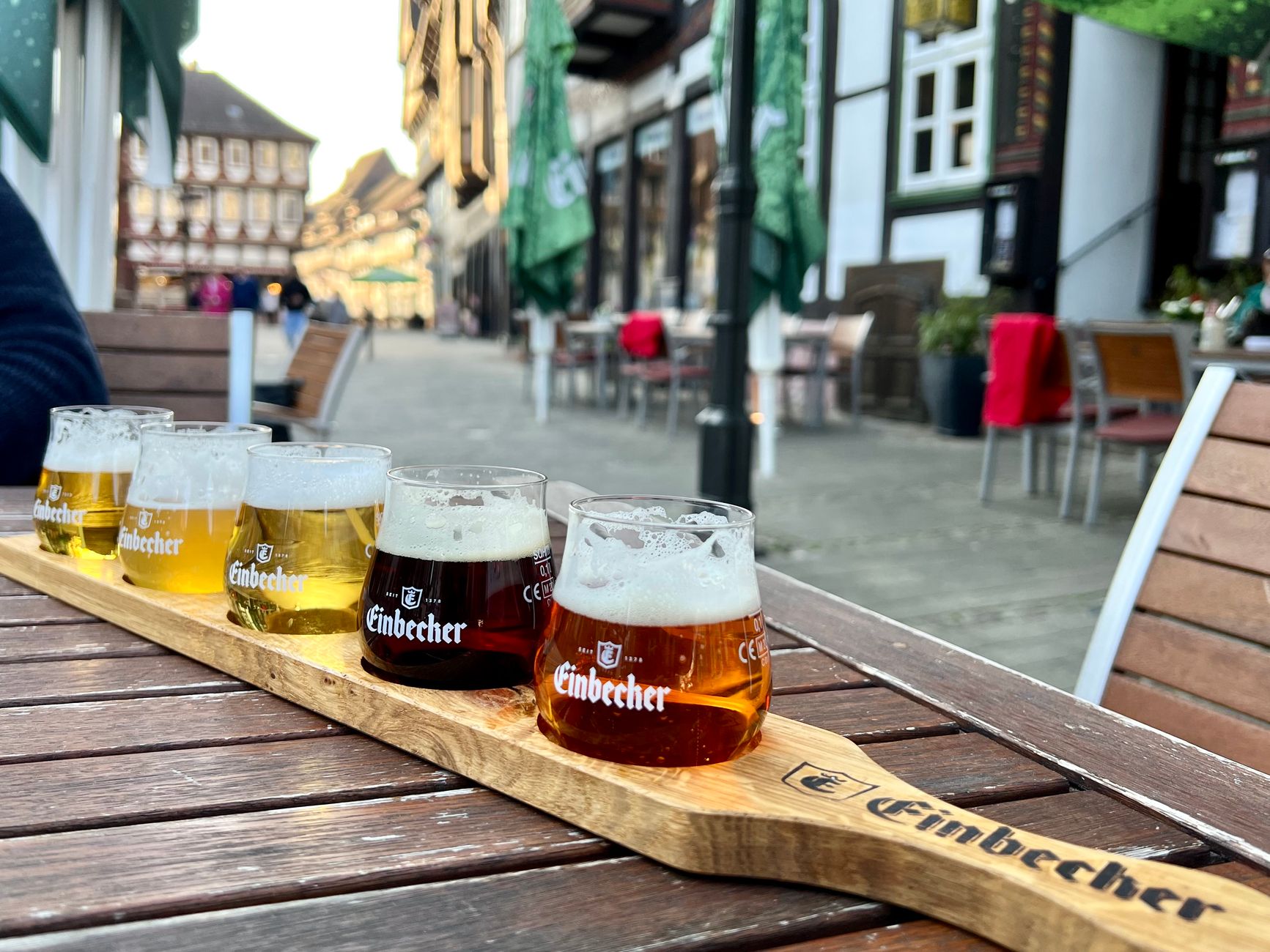 Beer garden with wooden tables, green trees, and sunlight in Saguramo, Georgia.