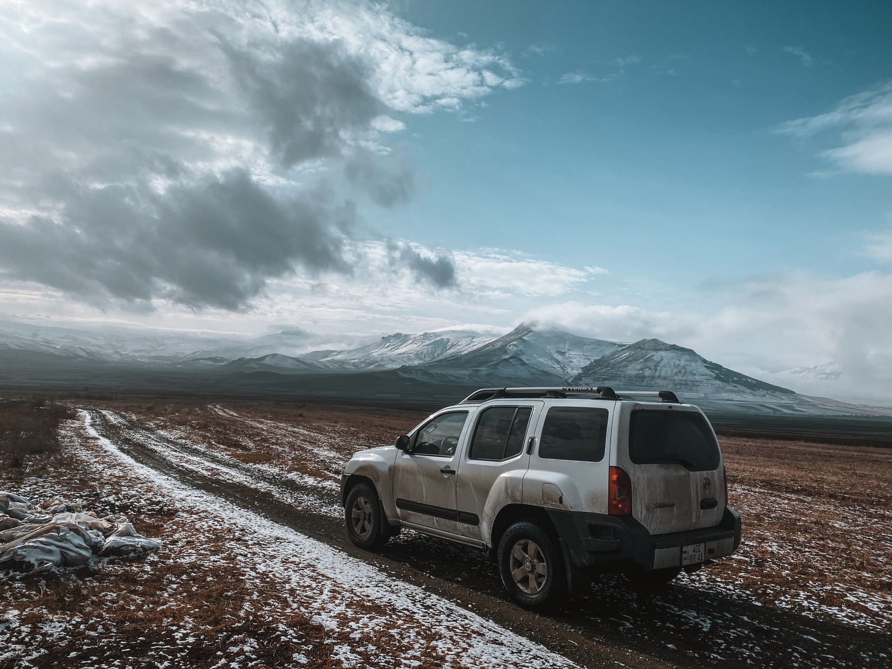 A white SUV driving along a mountain road in Adjara against a backdrop of charming scenery