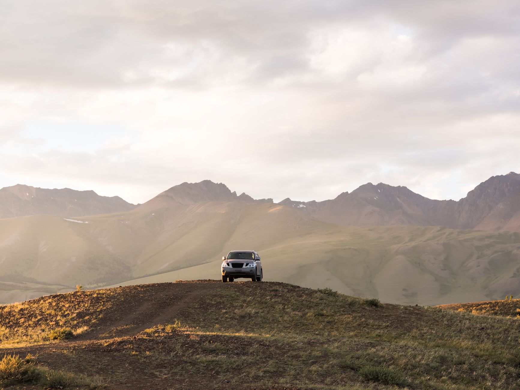 White 4x4 vehicle parked on a rocky road against the backdrop of the Caucasus mountains